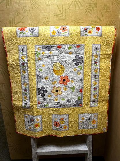 Handmade quilted baby blanket with bumblebees, flowers and yellow background