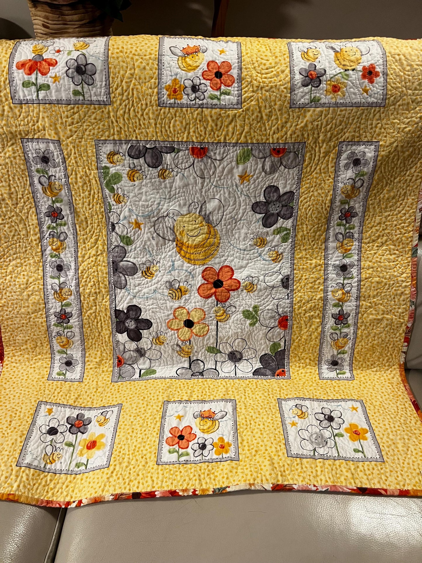 Handmade quilted baby blanket with bumblebees, flowers and yellow background