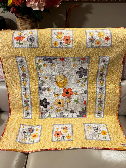 Handmade quilted baby blanket with bumblebees, flowers and yellow background