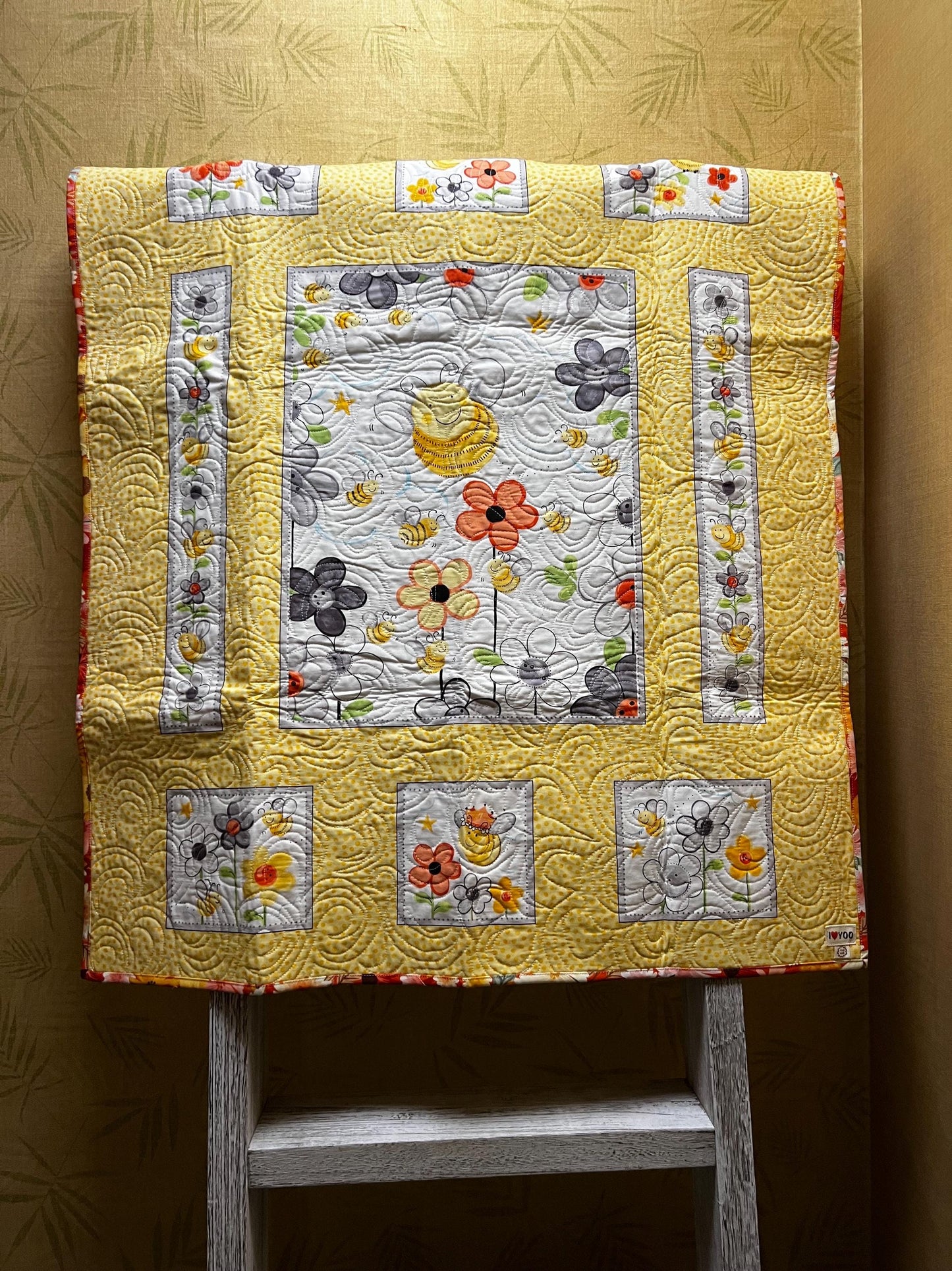 Handmade quilted baby blanket with bumblebees, flowers and yellow background